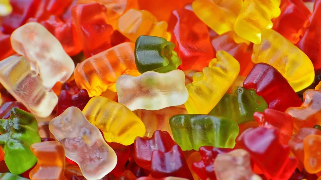 A close-up pile of translucent red, yellow, orange, and green gummy bears